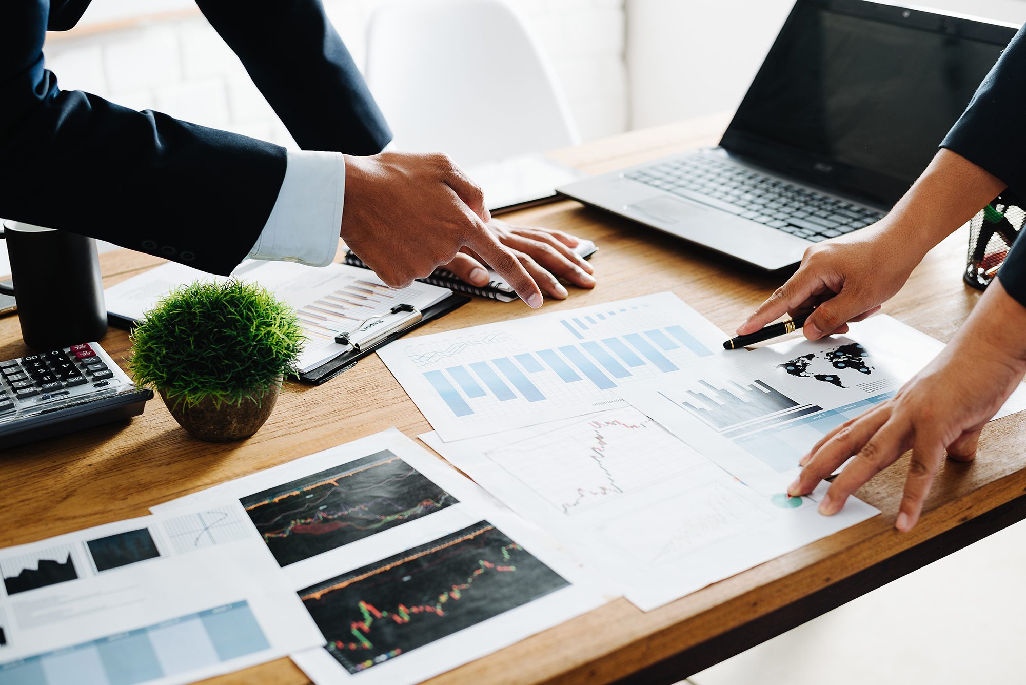 Closeup_Of_Professionals_Pointing_At_Charts_On_Desk